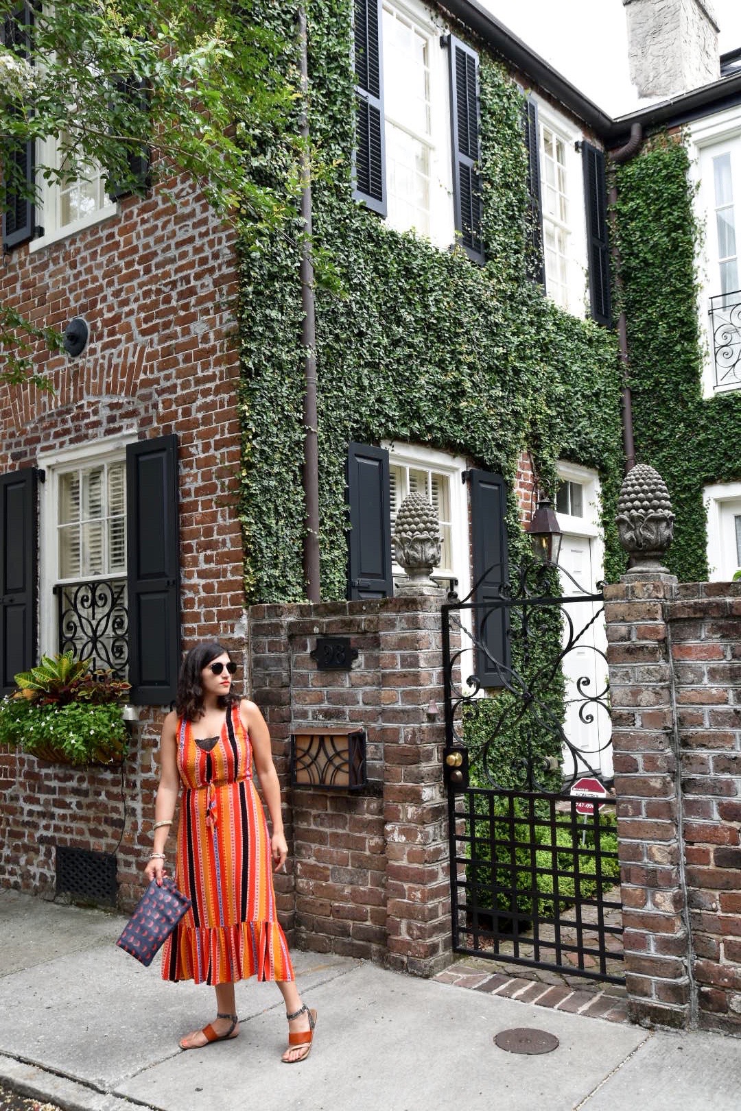 Aya wearing Elsa Fine dress Charleston SC in front of building covered in greenery