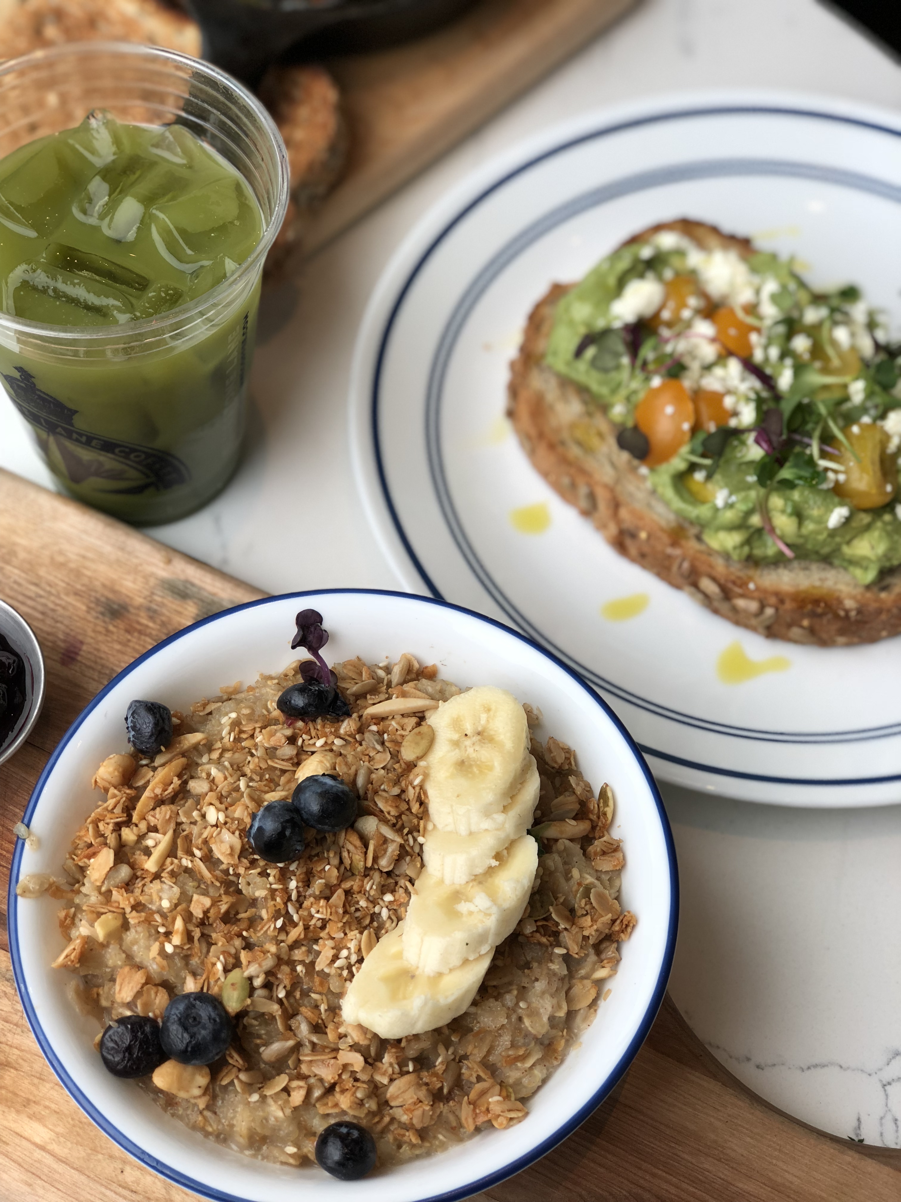 A2F flatlay of quinoa and porridge coconut and blueberry bowl, avocado smash, kale juice and baked eggs at Bluestone Lane in D.C.