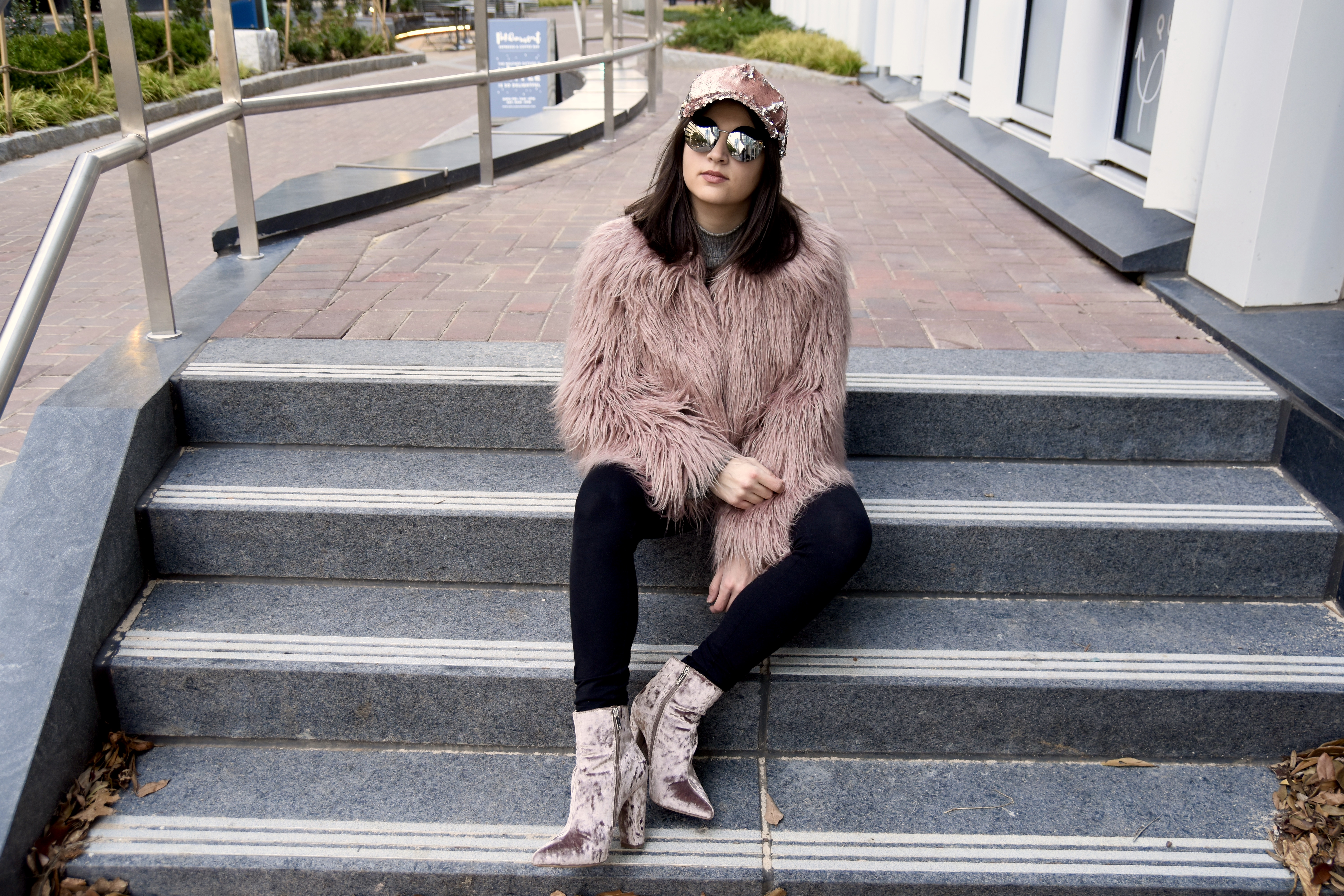 Dania sitting in Vince Camuto pink faux fur and jessica simpson boots in blush